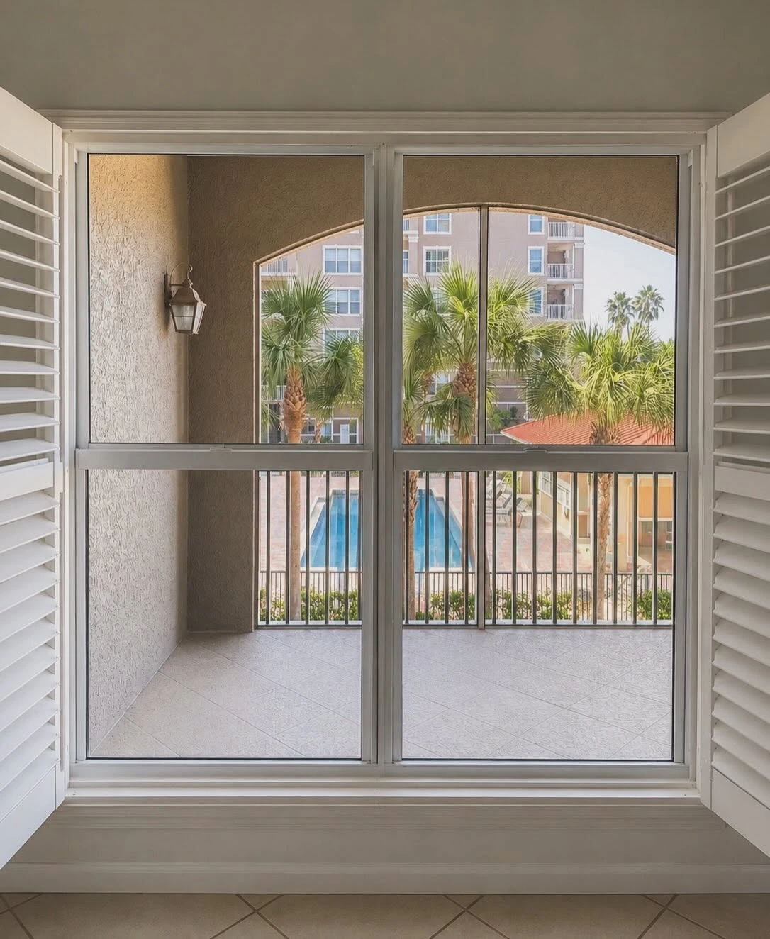 Arched window and sliding door opening to a screened balcony with pool view