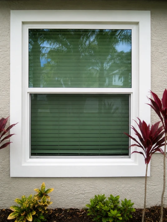 White single hung replacement window with wide trim on a stucco exterior