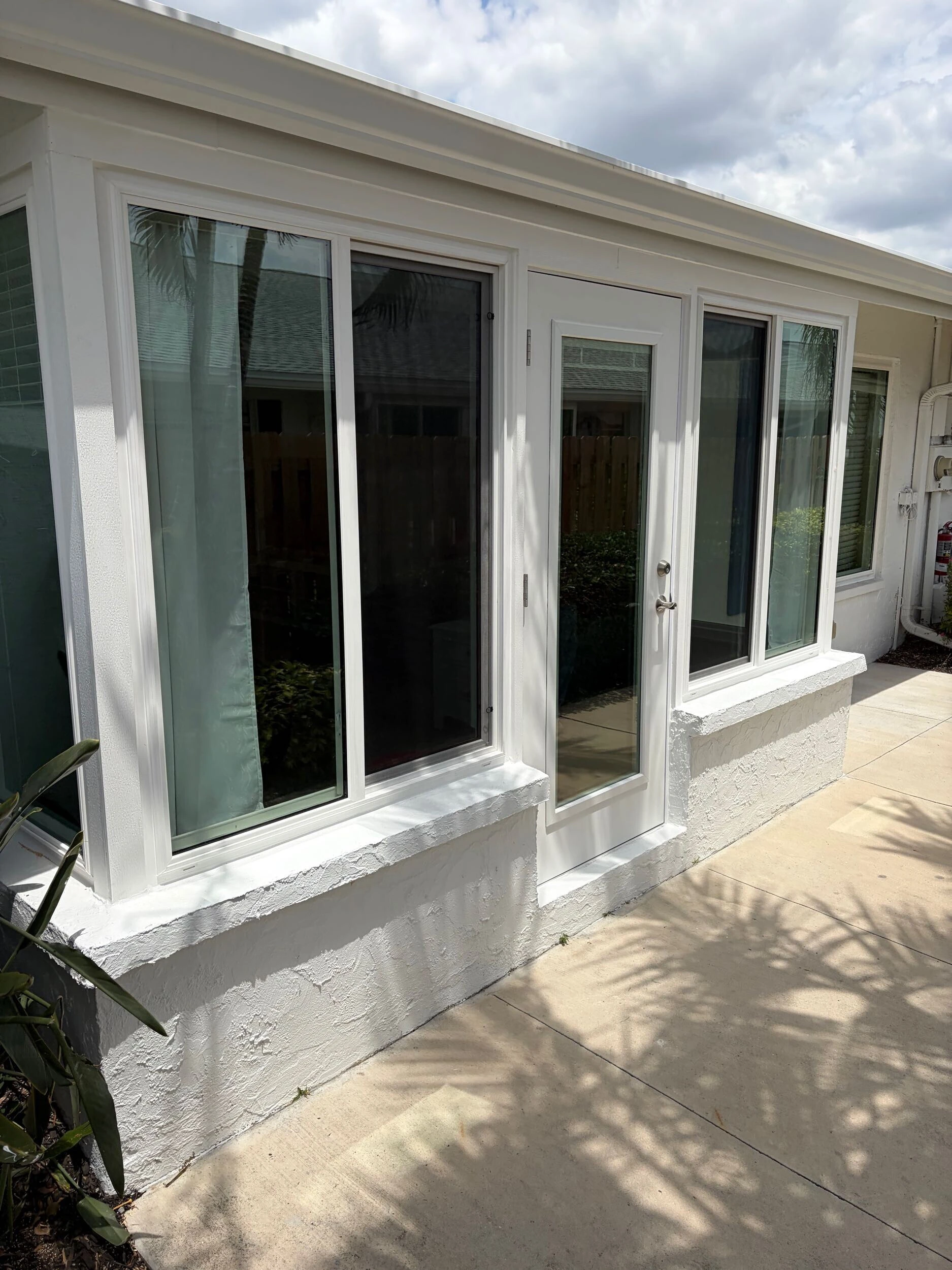 New white windows and a glass patio door on a stucco home exterior