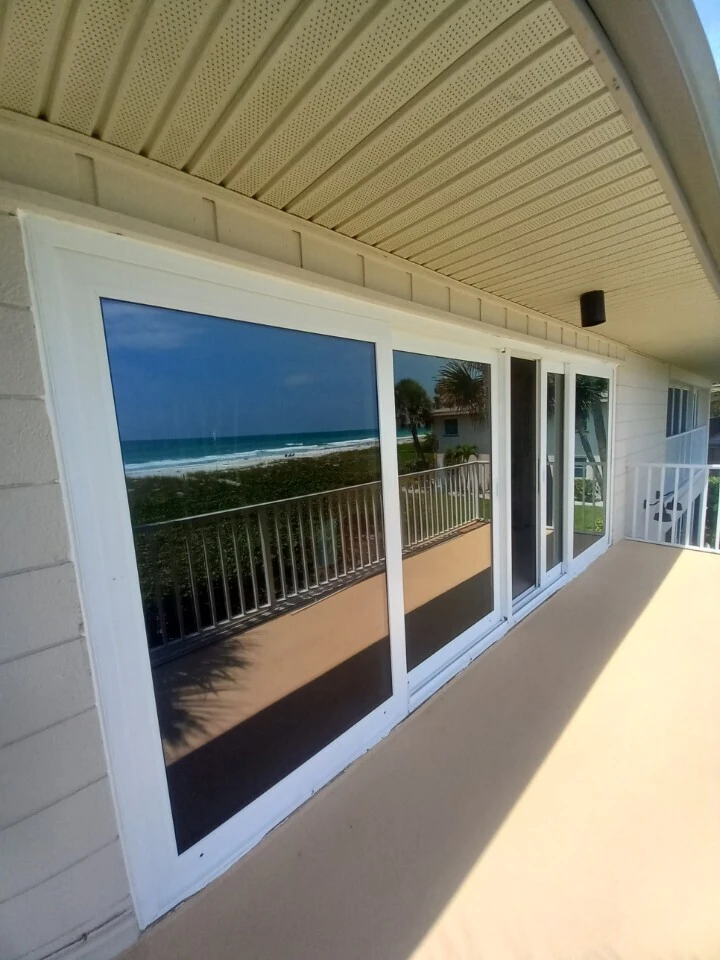 Impact-rated sliding glass doors on a beachfront balcony with Gulf views