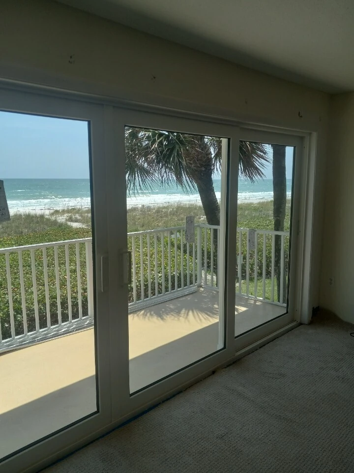 Sliding glass doors opening onto a beachfront balcony overlooking the Gulf