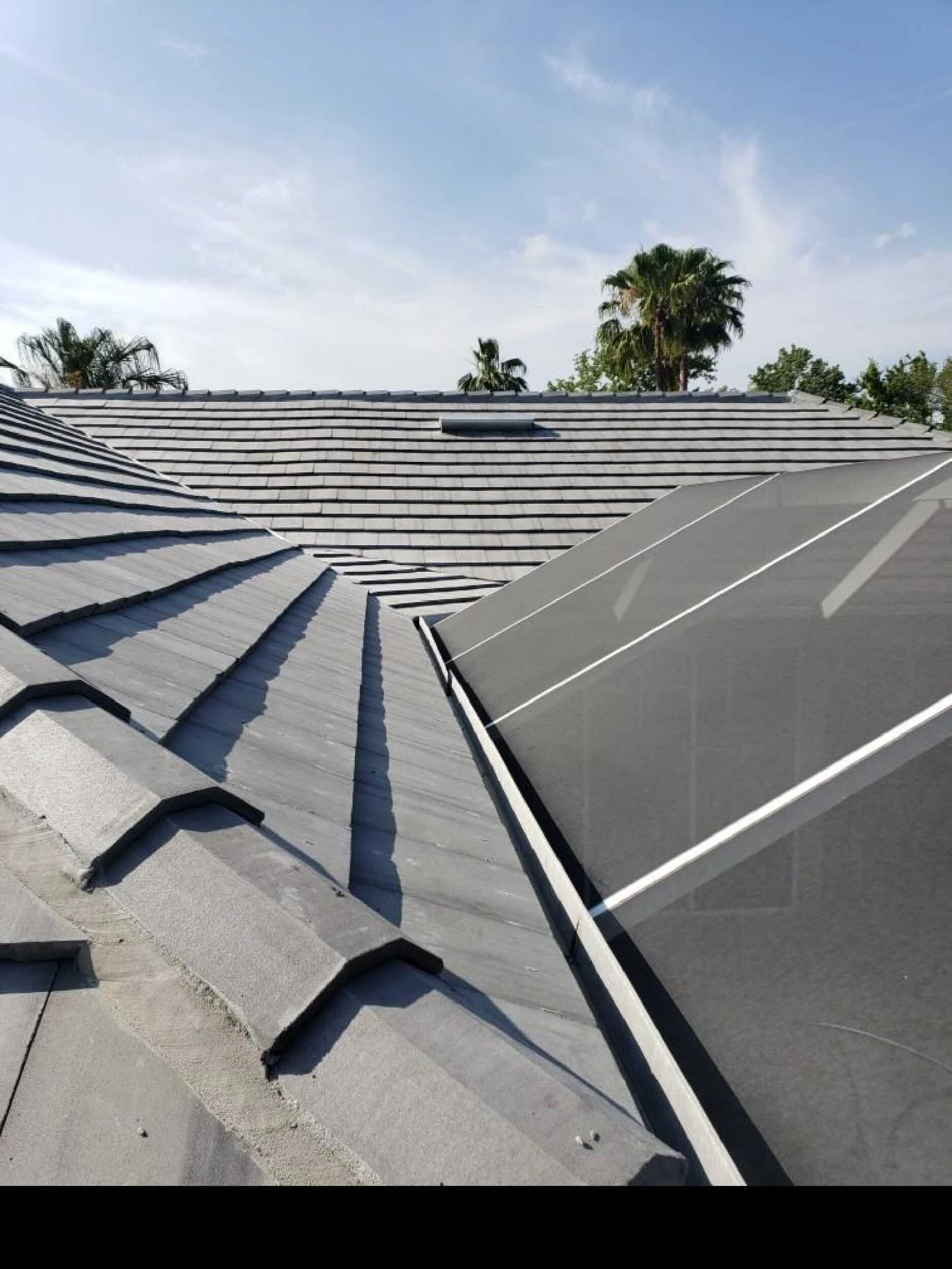 Gray concrete tile roof meeting a screened lanai enclosure on a Florida home
