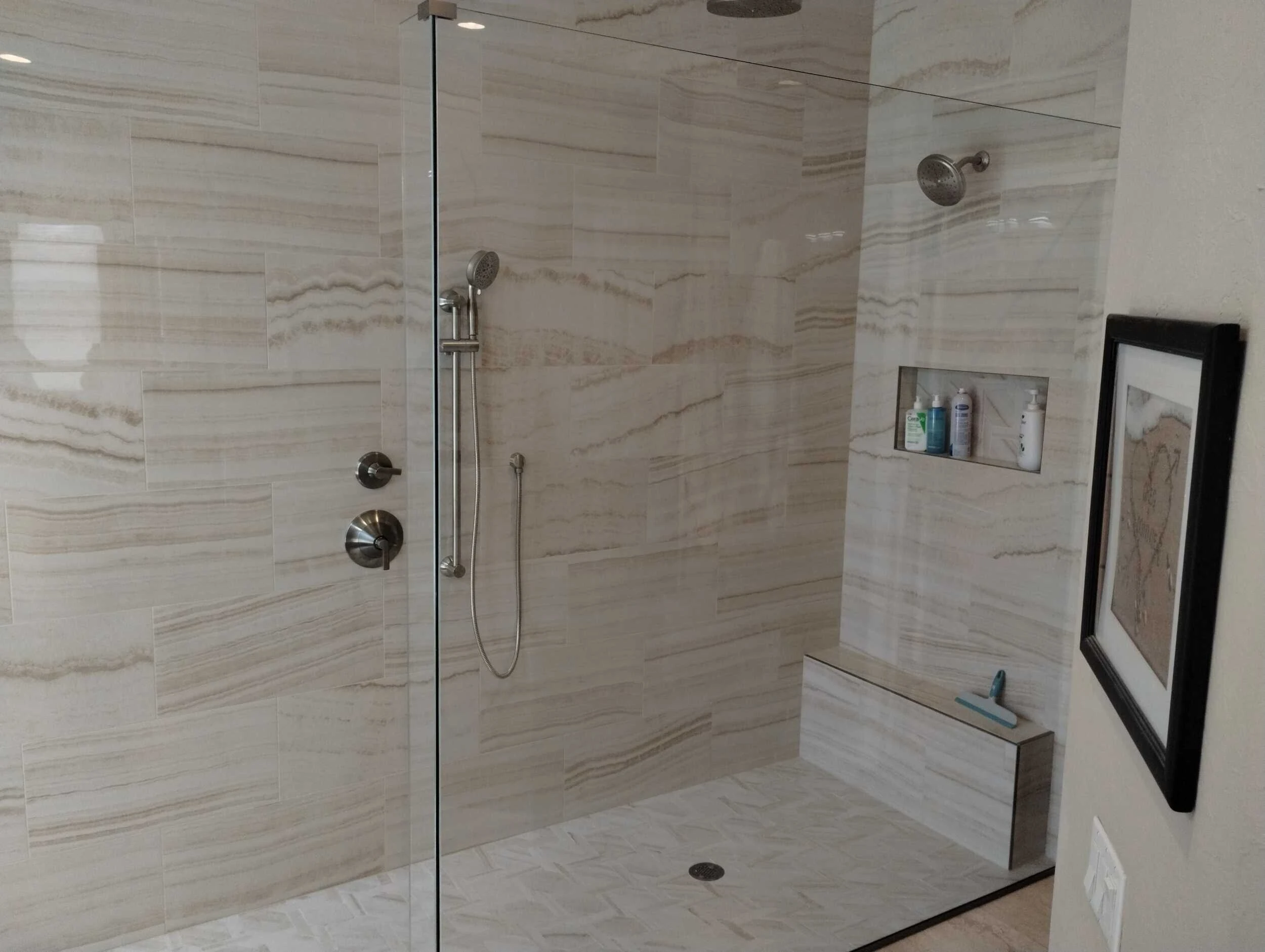 Walk-in shower with cream stone-look tile, corner bench and a shelf niche