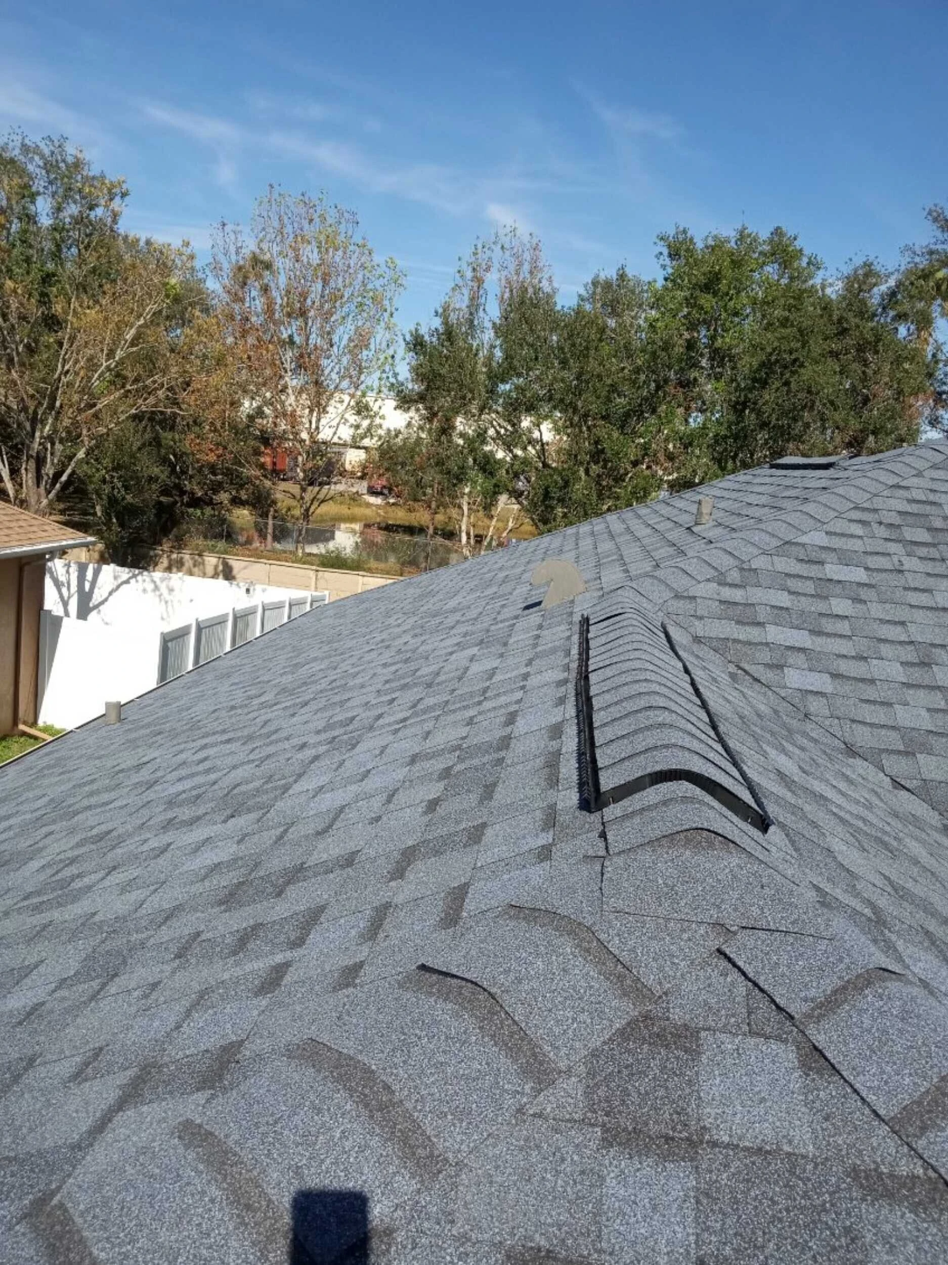 Asphalt shingle roof with new ridge cap shingles being installed