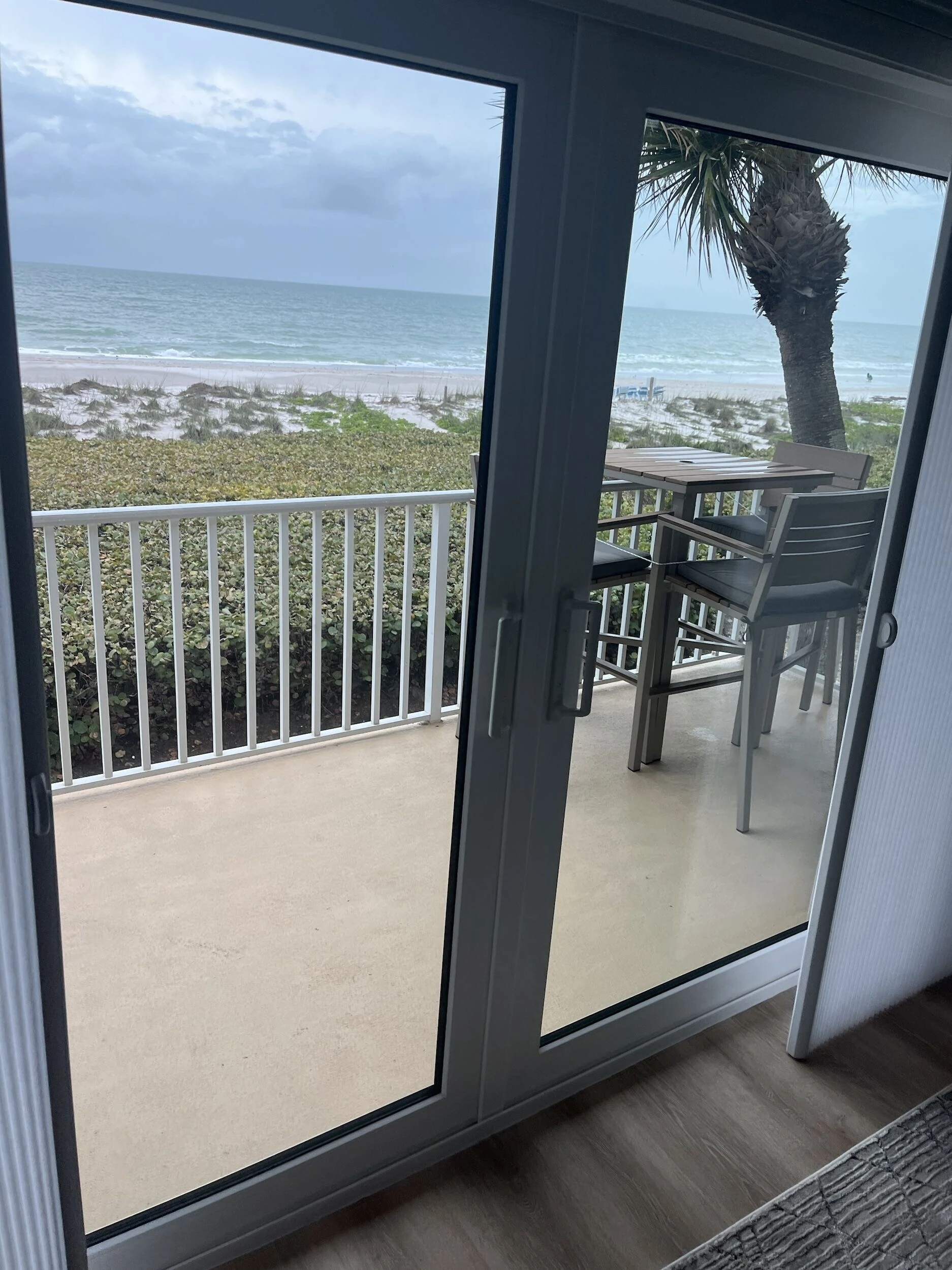 Impact sliding glass doors opening to a balcony with beach and Gulf views