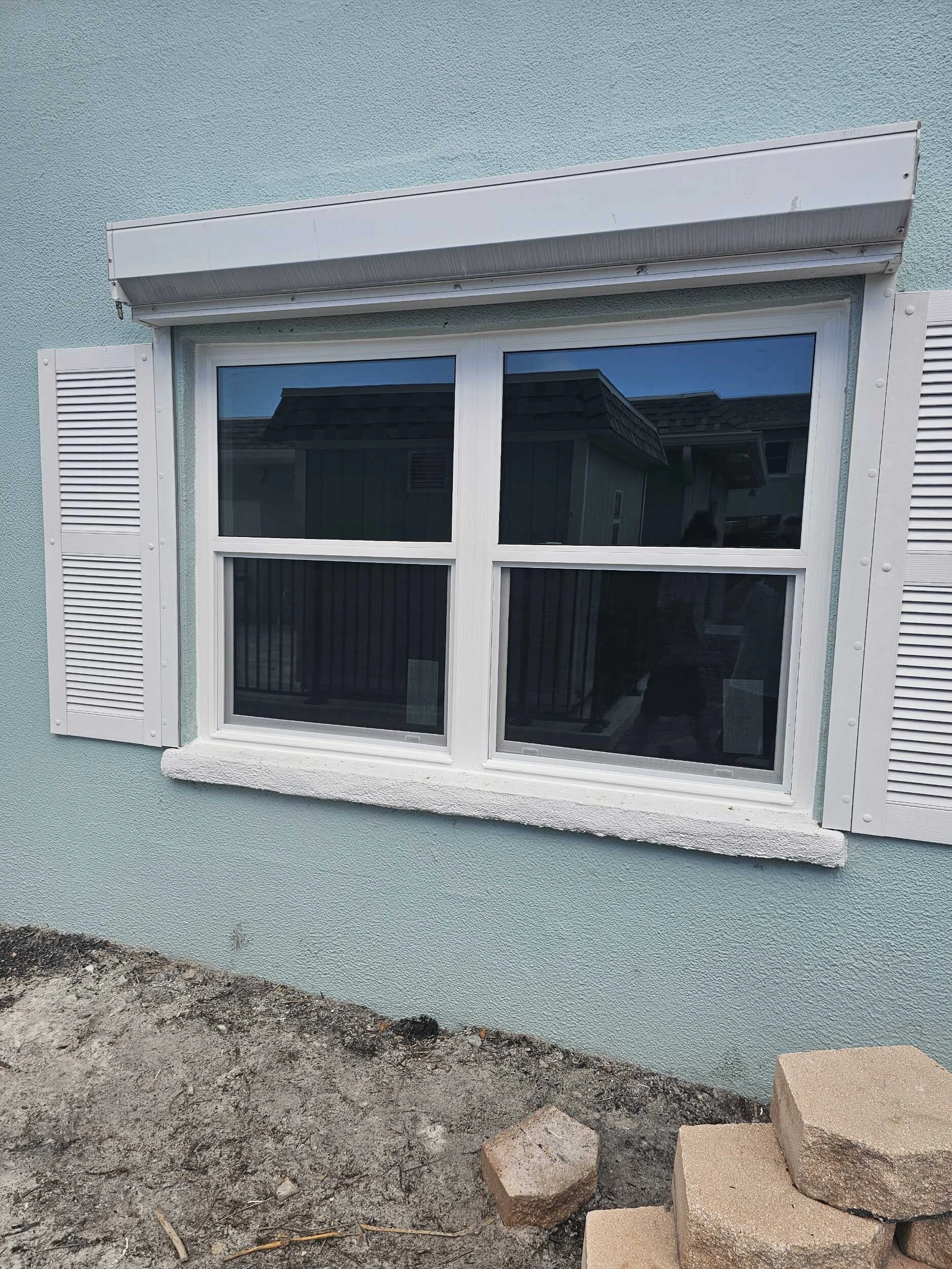 Replacement window with roll-down hurricane shutter and white bahama shutters