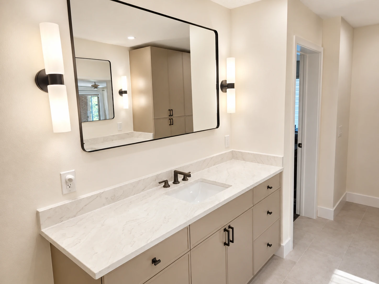 Remodeled bathroom vanity with quartz countertop, undermount sink and black framed mirror