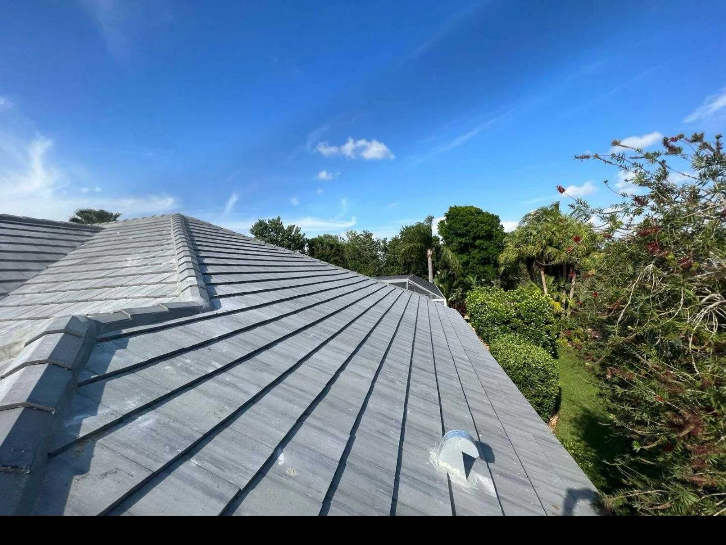 New gray concrete tile roof on a Florida home surrounded by tropical landscaping