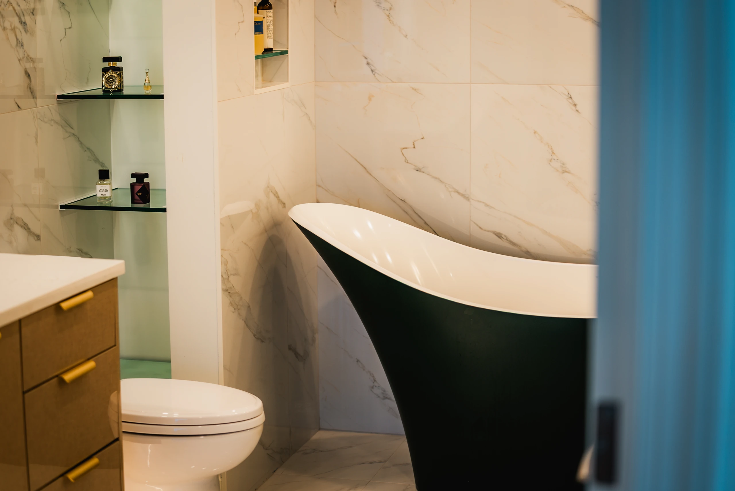 Bathroom with a green freestanding tub, marble-tiled walls and a wood vanity