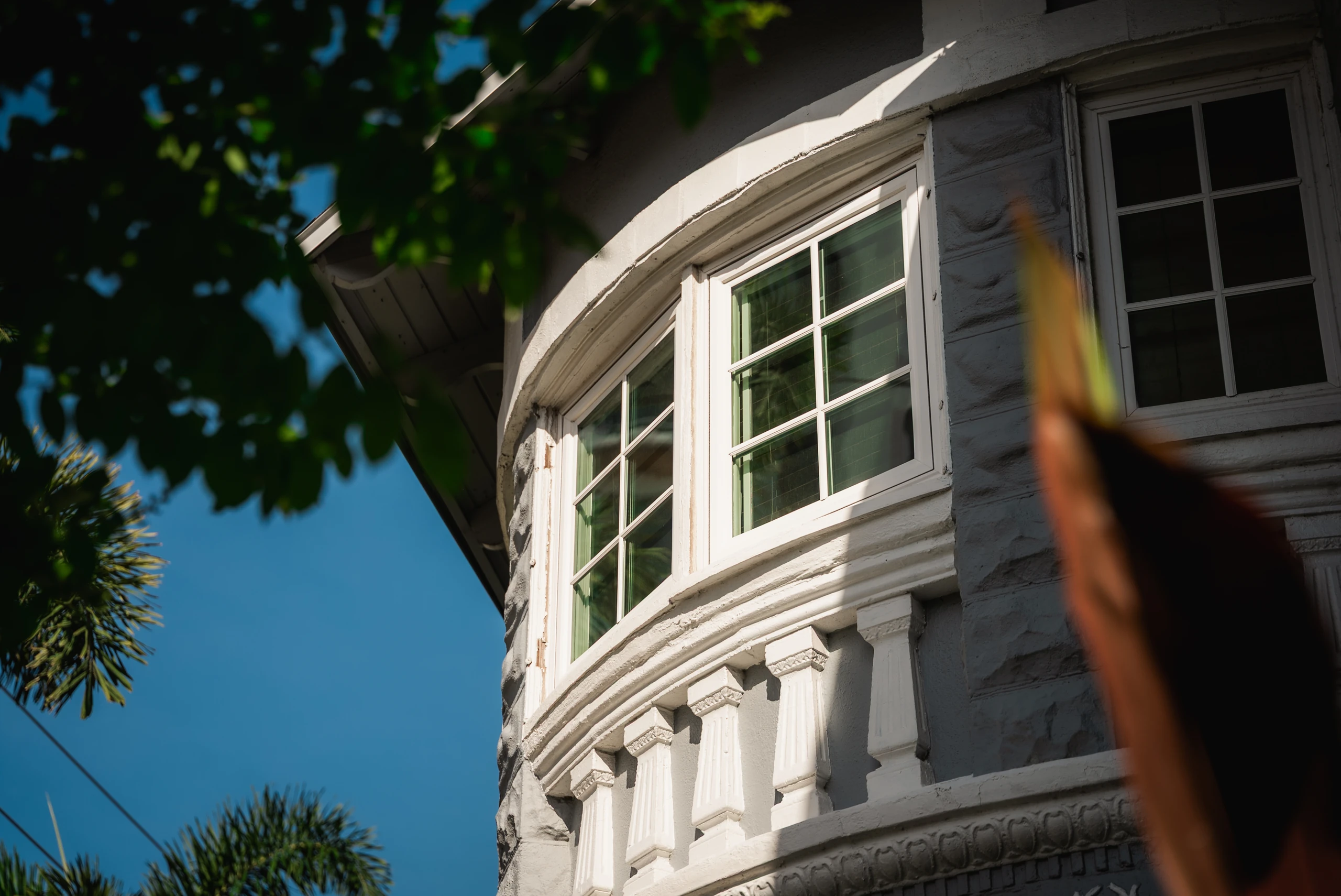 Curved bay of white divided-light windows on a gray clapboard home