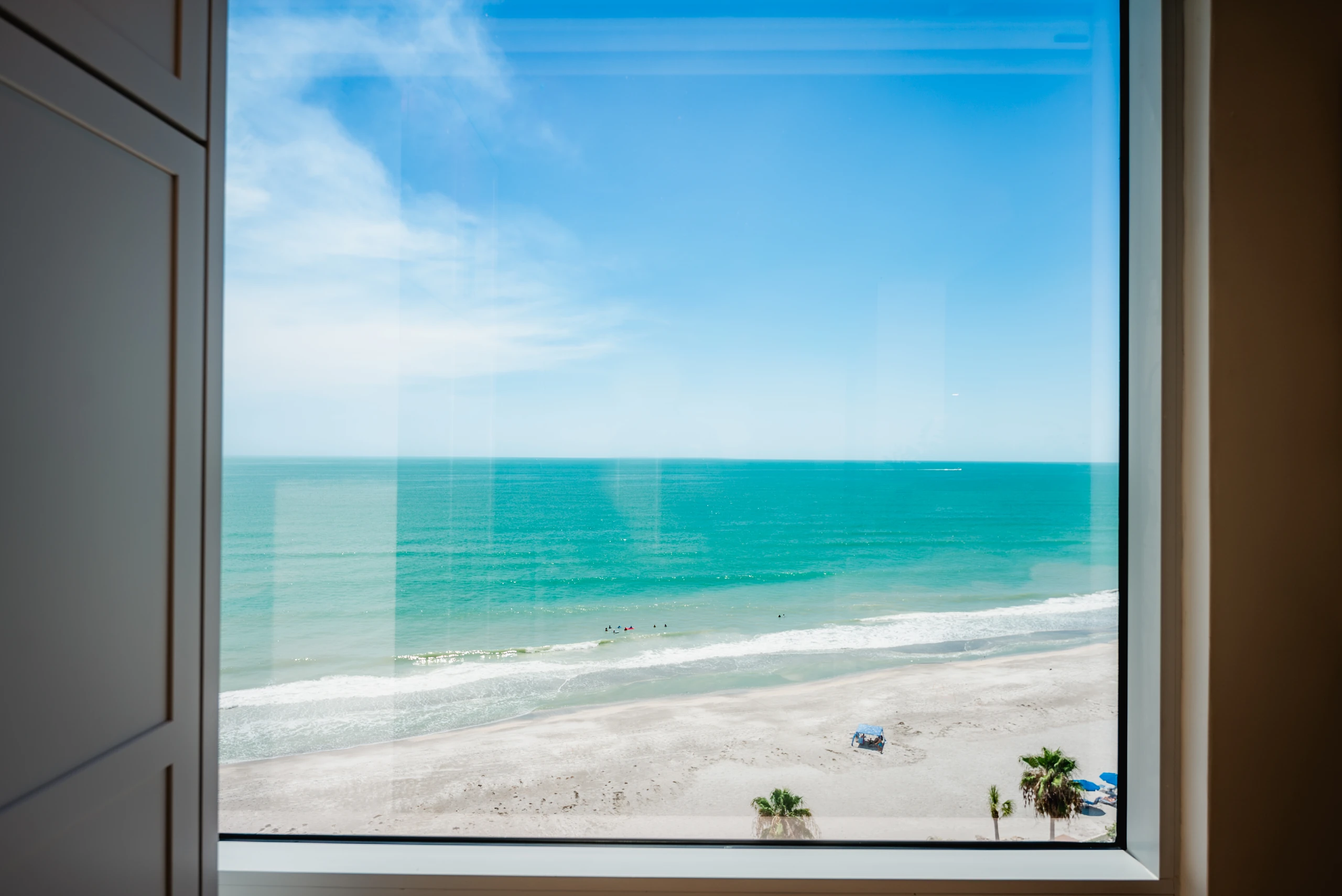 Picture window framing the beach and Gulf from inside a condo