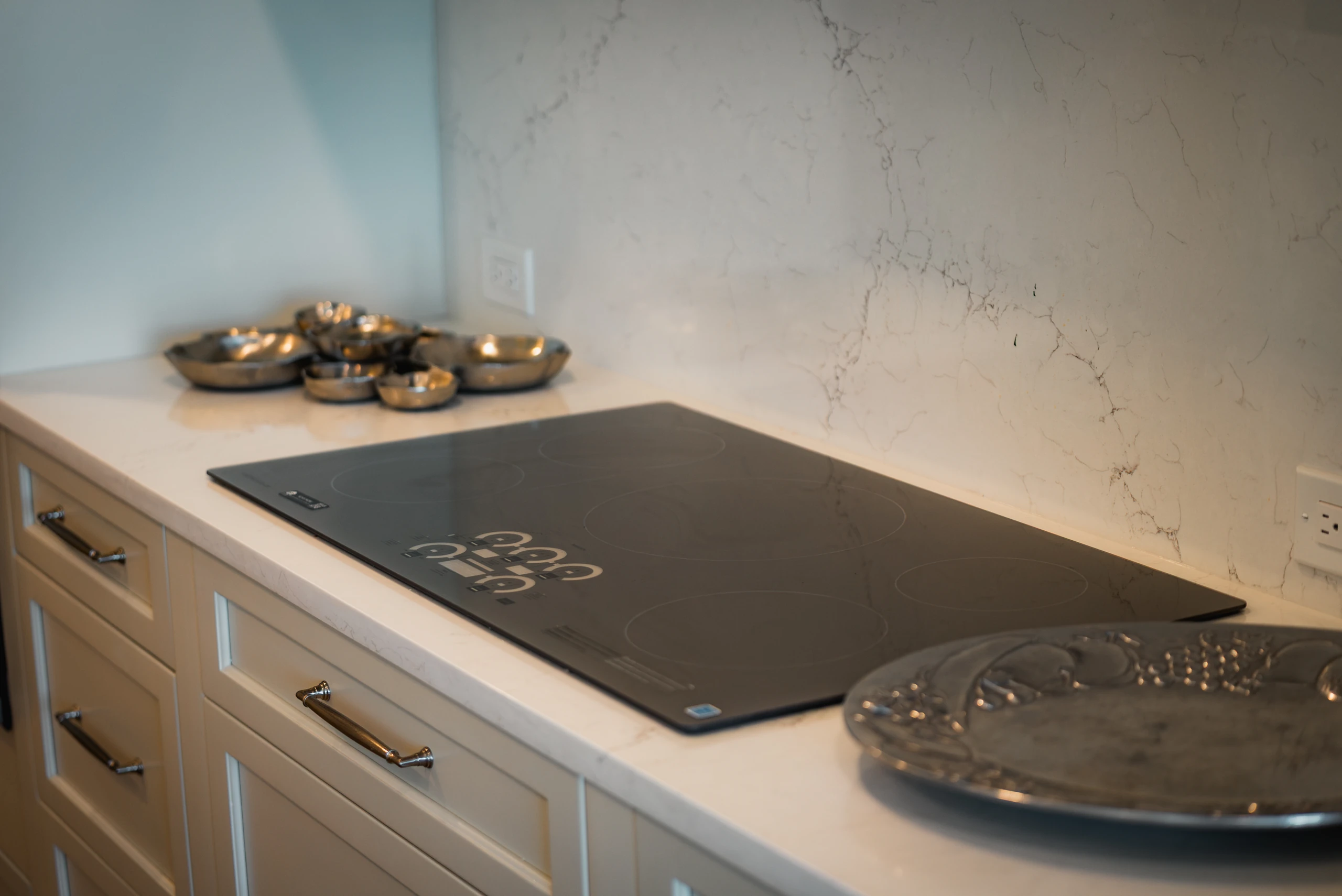Induction cooktop set into a quartz counter with a marble-look backsplash