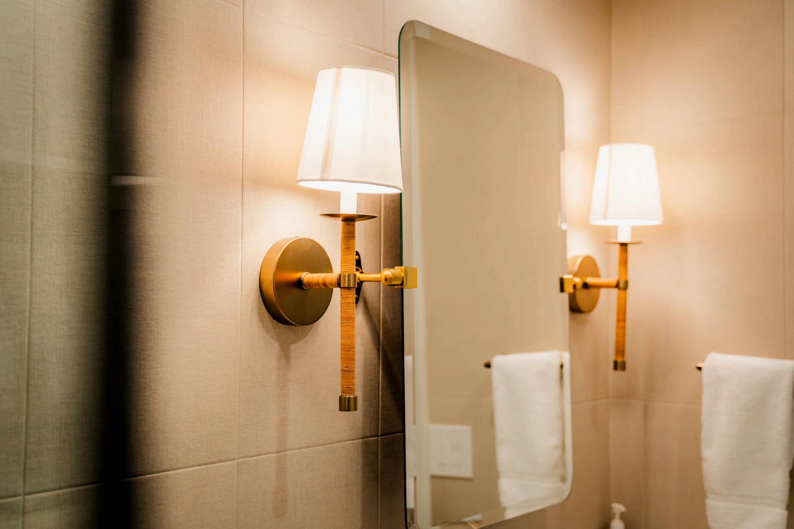 Bathroom wall sconces flanking a mirror above a towel bar