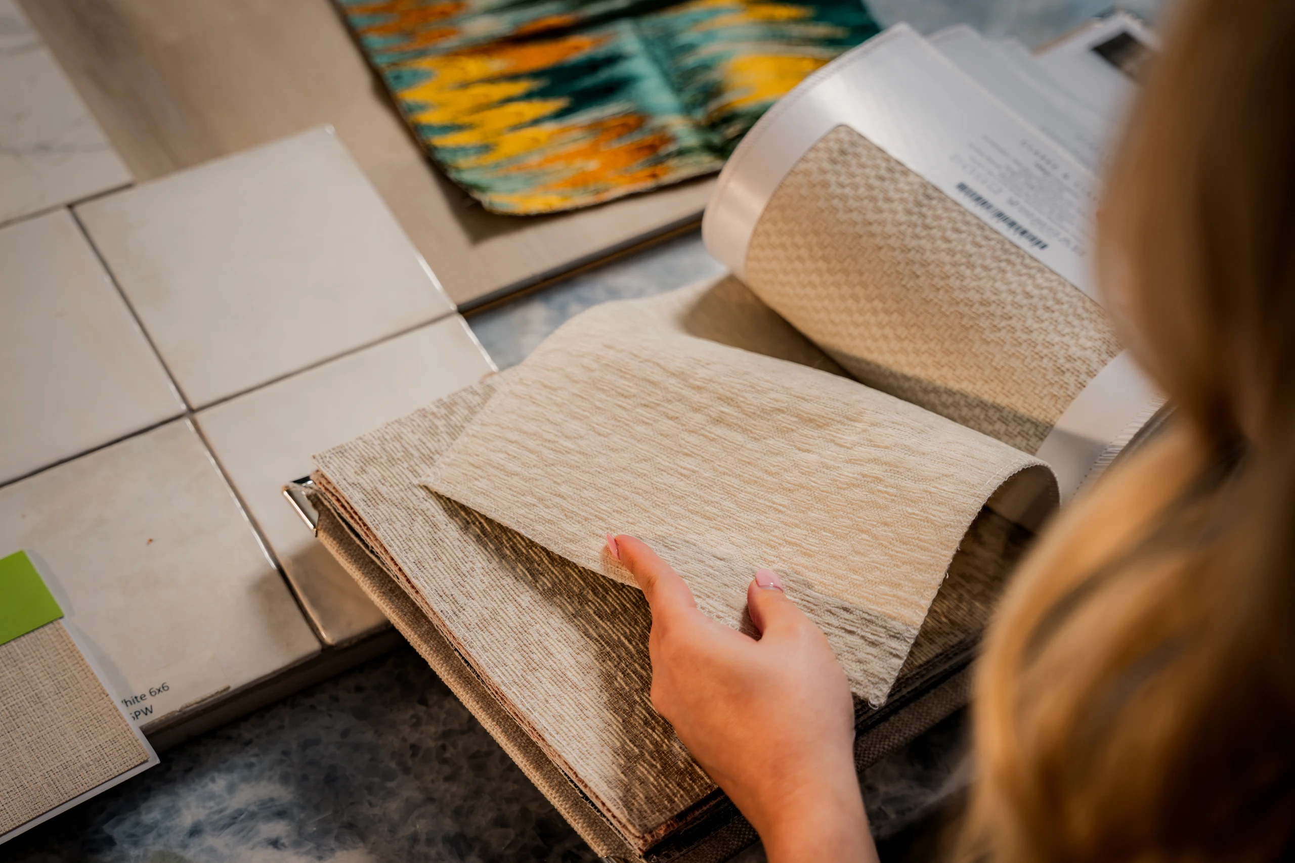 Designer paging through fabric and tile samples during a design consultation