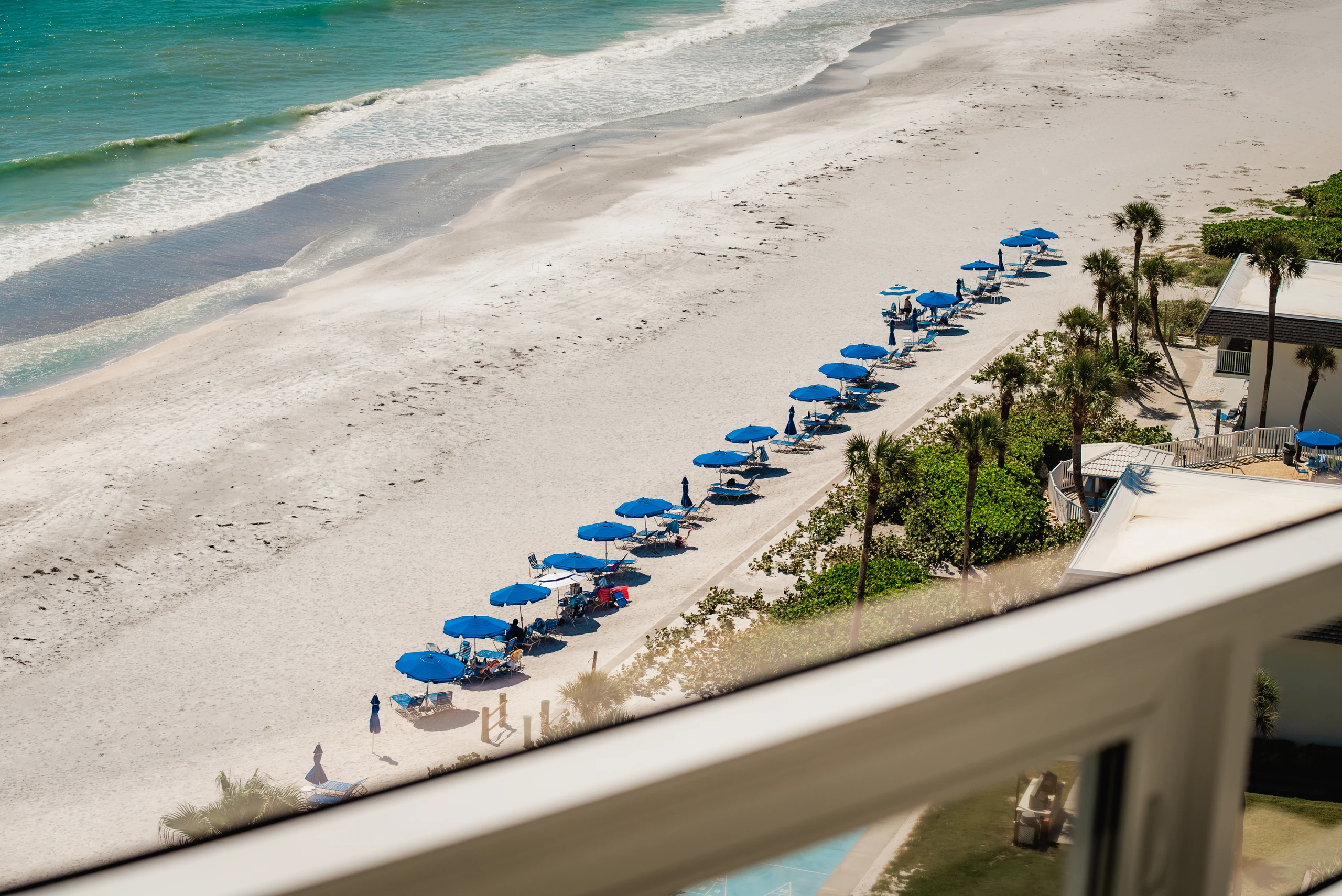 Aerial view of a Gulf beach lined with blue umbrellas