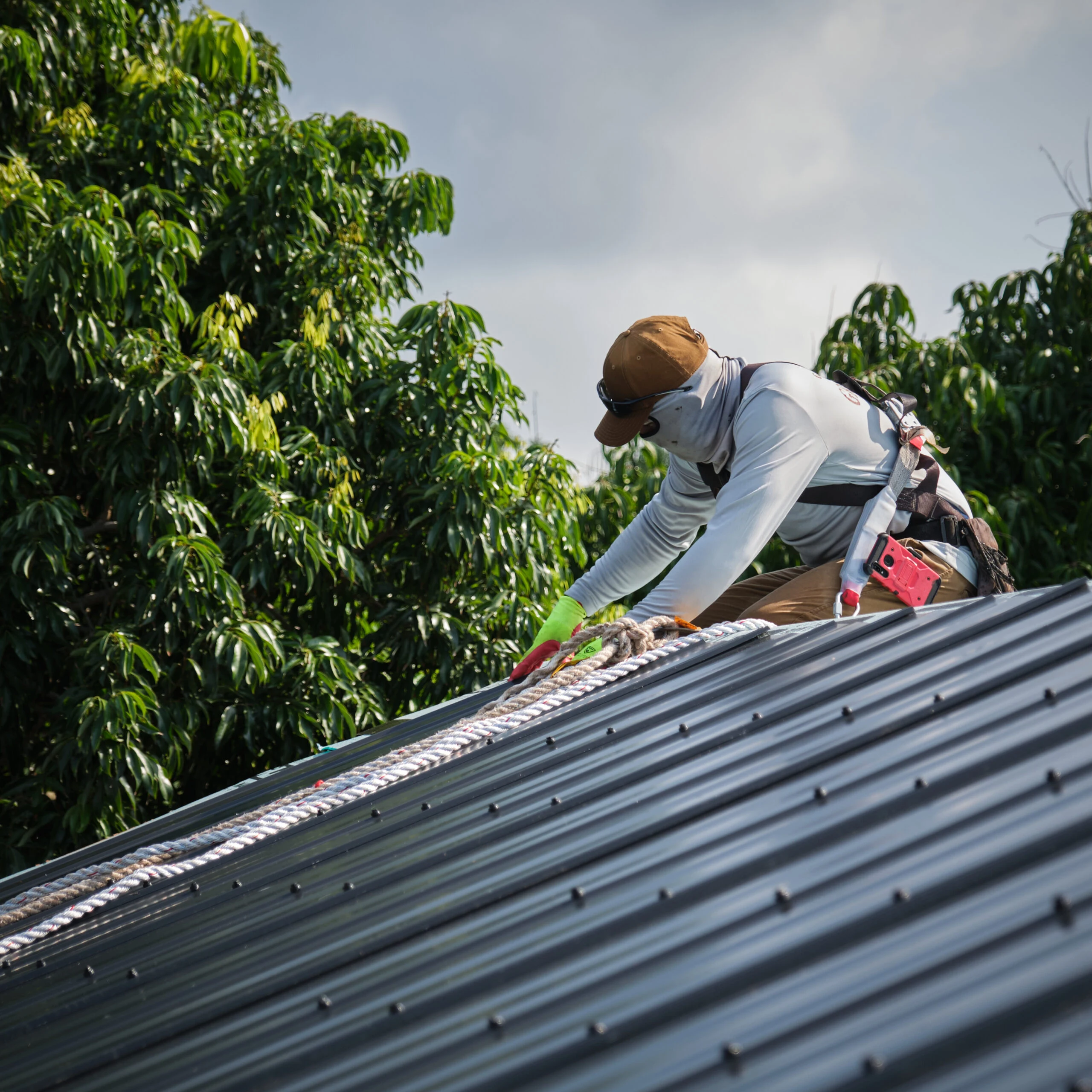 Roofer fastening a standing seam metal roof panel
