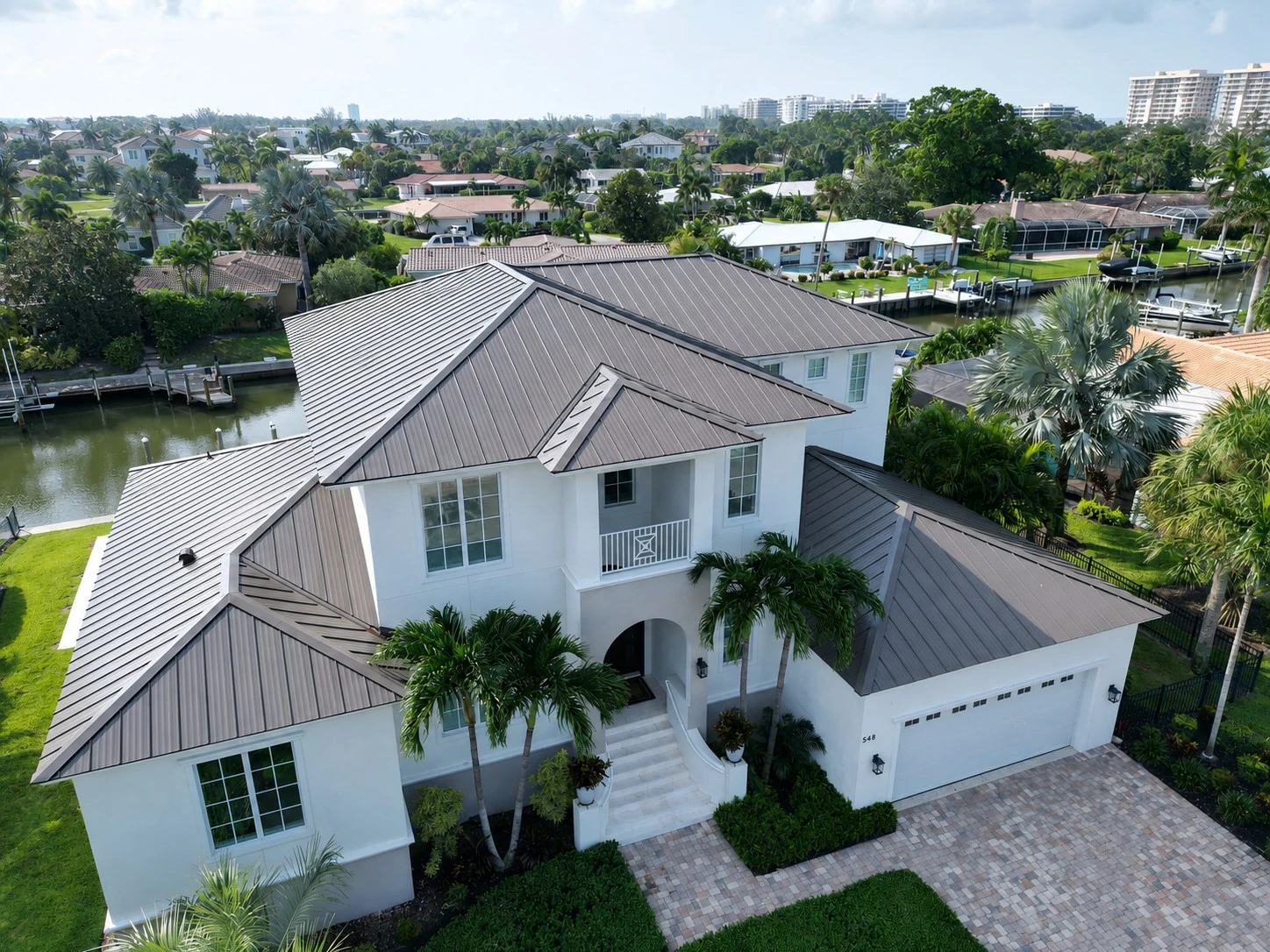 Aerial view of a waterfront home with a standing seam metal roof