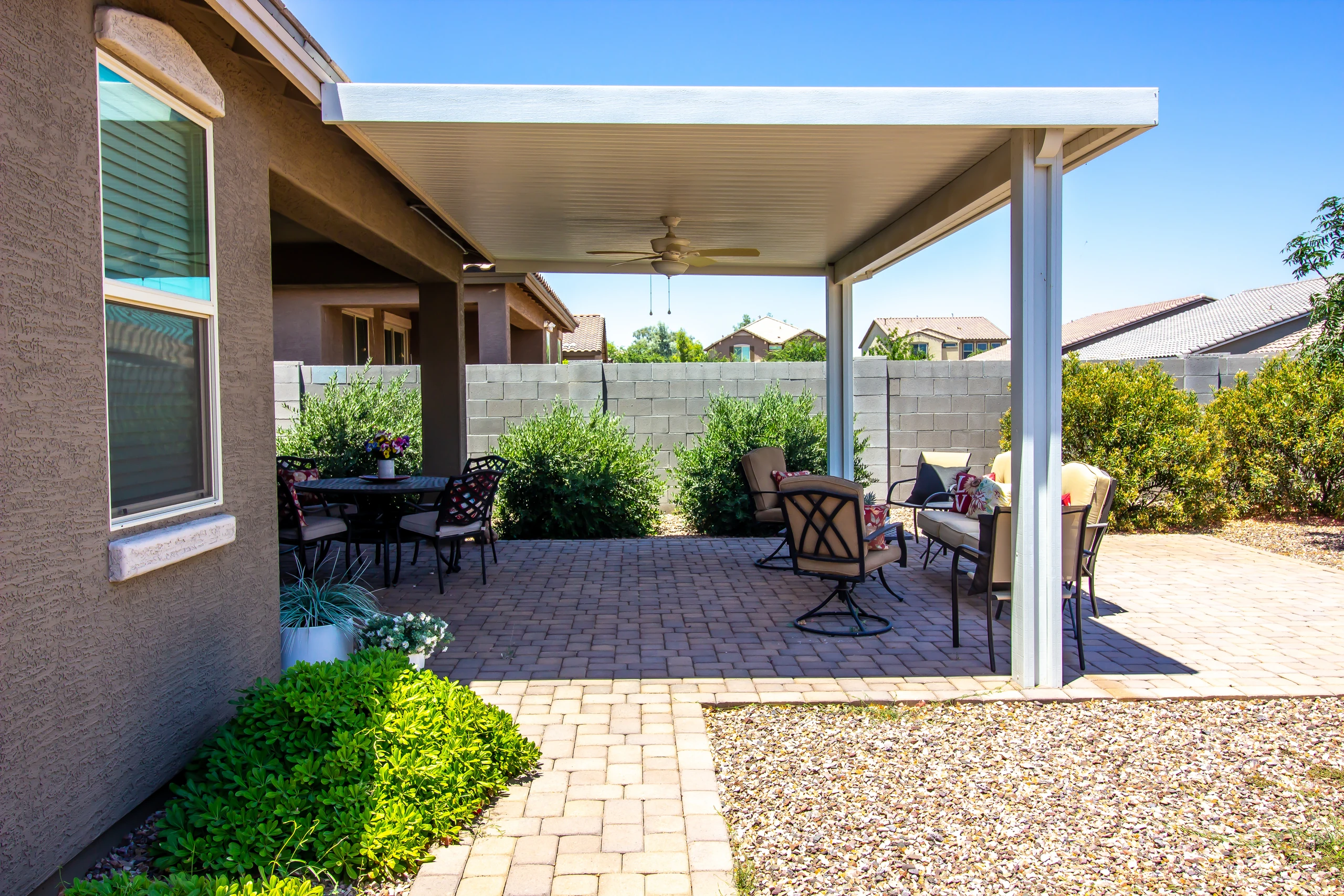 Covered patio with a flat aluminum roof over a paver patio and seating