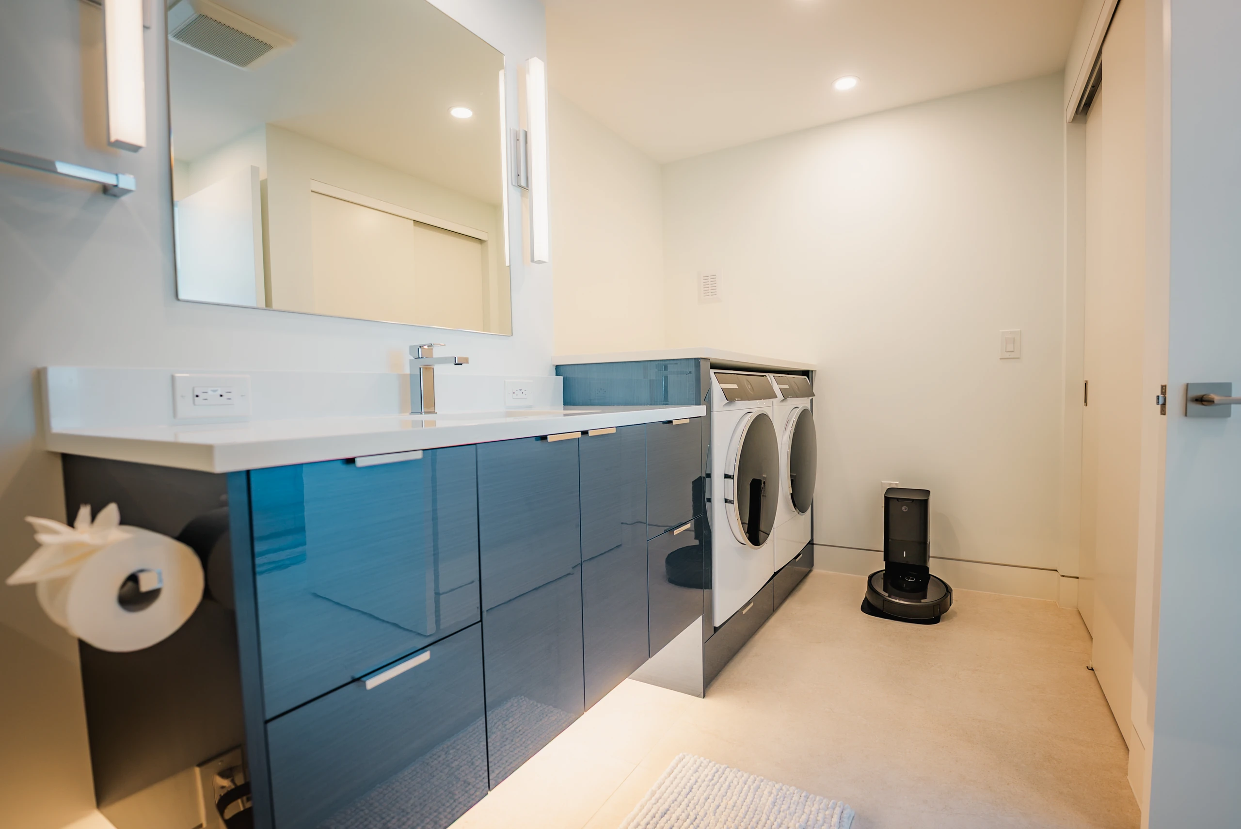 Laundry room with glossy blue cabinets, a quartz counter and front-load washer and dryer
