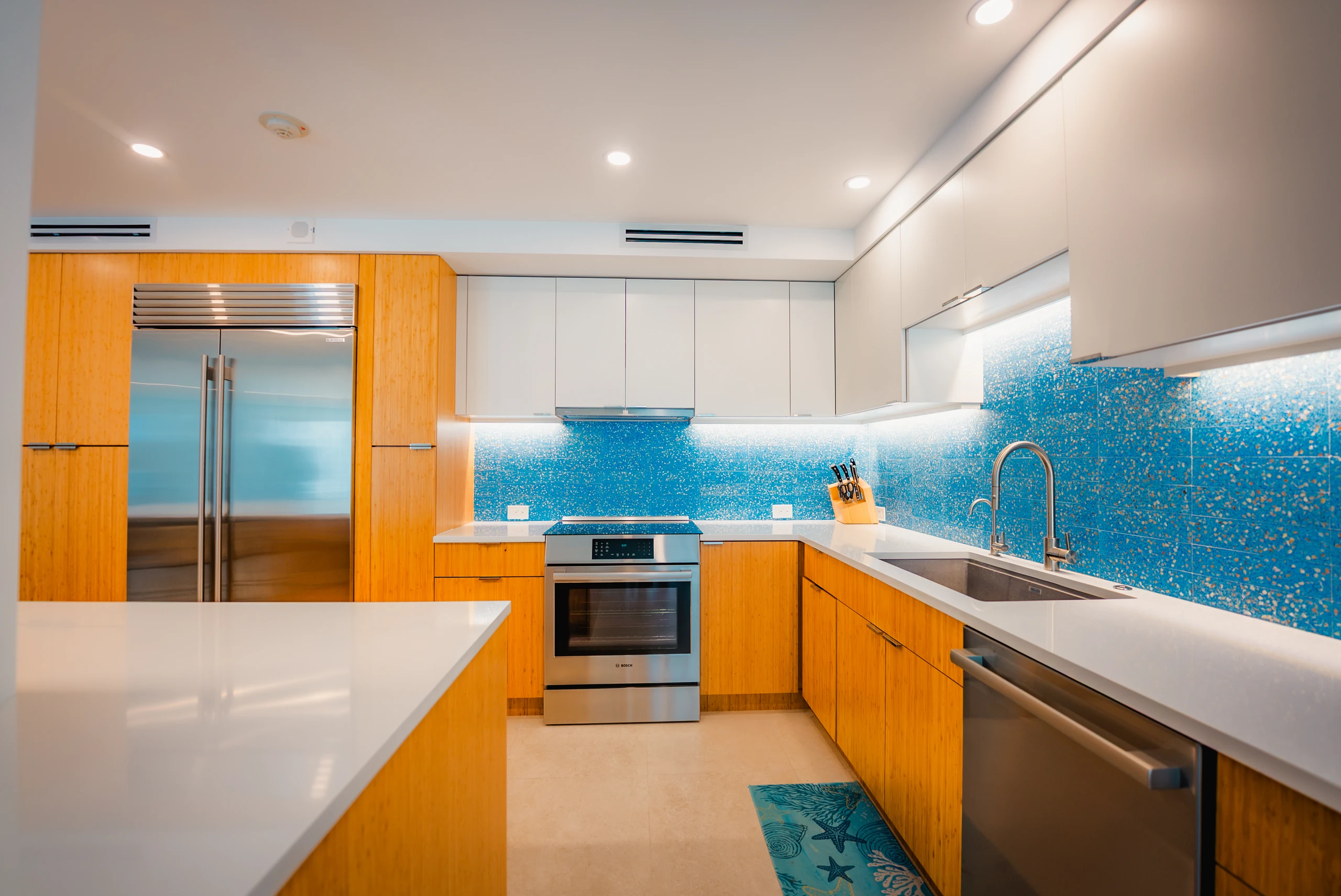 Kitchen with wood cabinets, a blue glass mosaic backsplash and quartz counters
