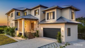 Modern two-story home lit at dusk with large windows and a metal roof