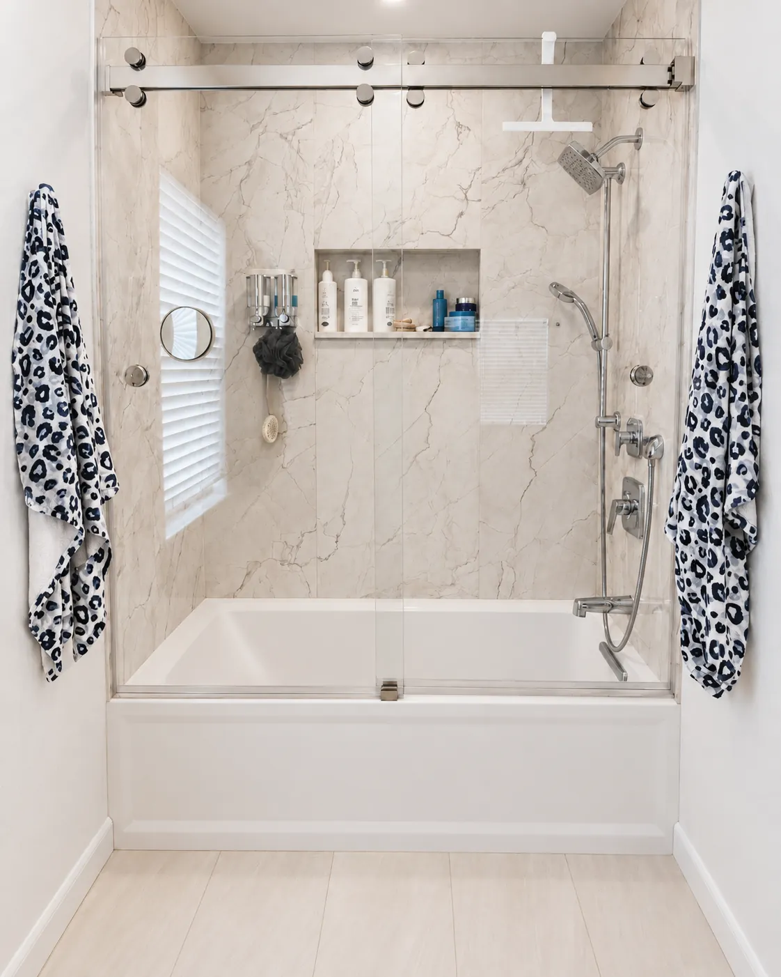 Tub and shower combination with marble-look tile and a frameless sliding glass door