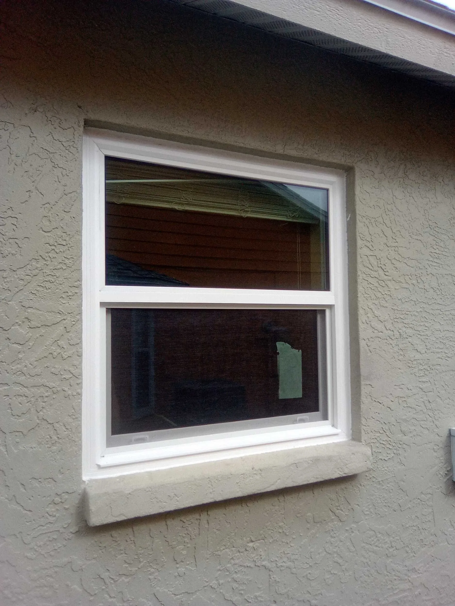 New single hung window installed in a beige stucco wall