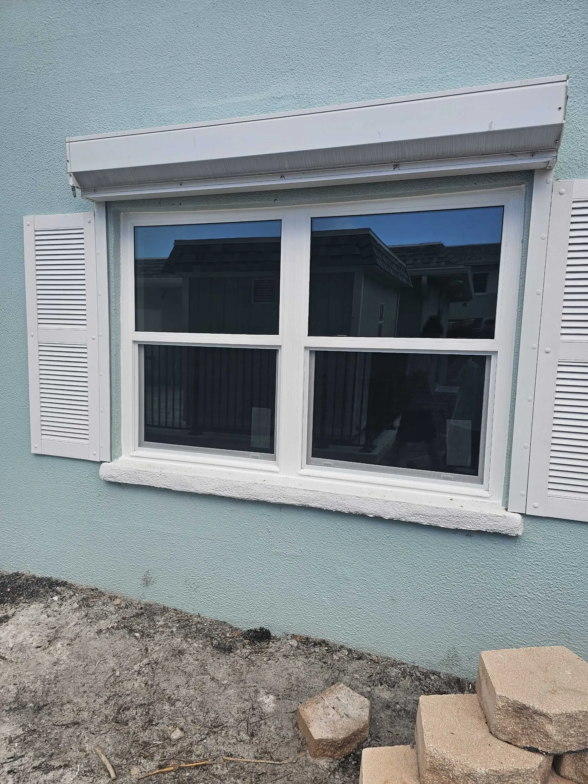 Replacement window with roll-down hurricane shutter and white bahama shutters