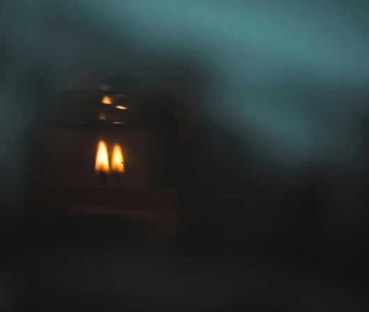 Dark foggy scene with a distant warm light.