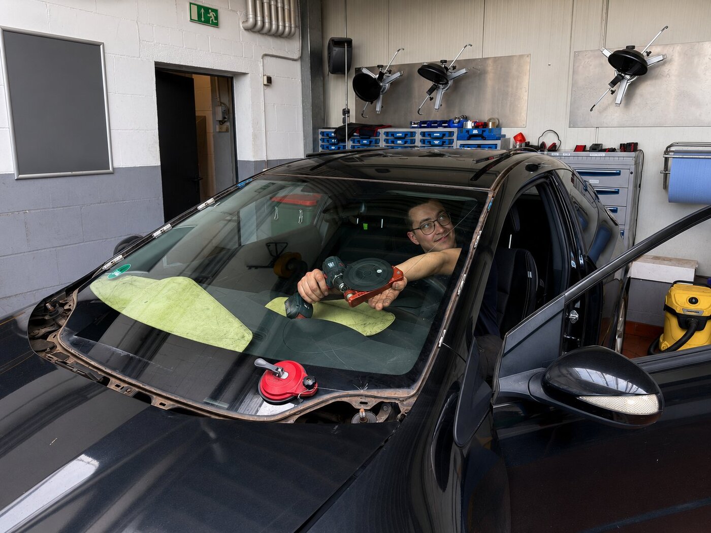 Mechaniker mit Saugnapf arbeitet an der Windschutzscheibe