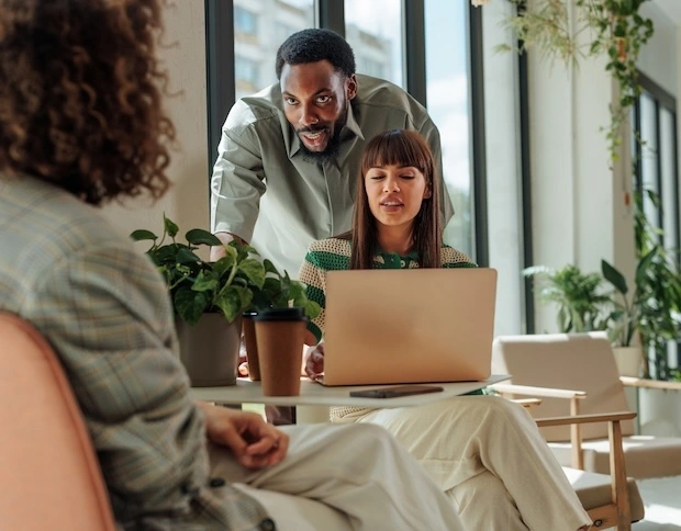 Three people talking and working on laptop.