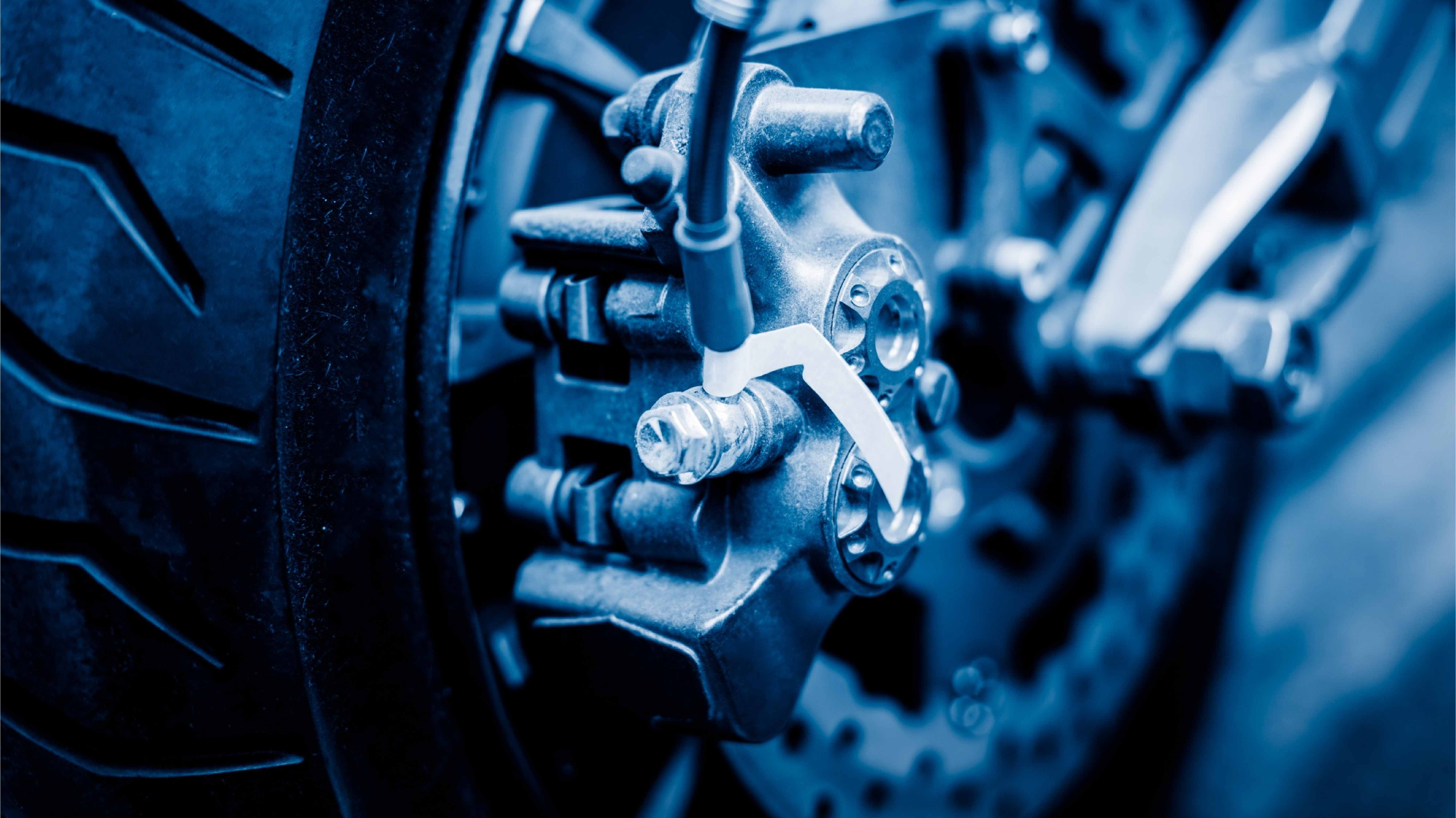Close-up of a motorcycle brake caliper and disc near the tire.