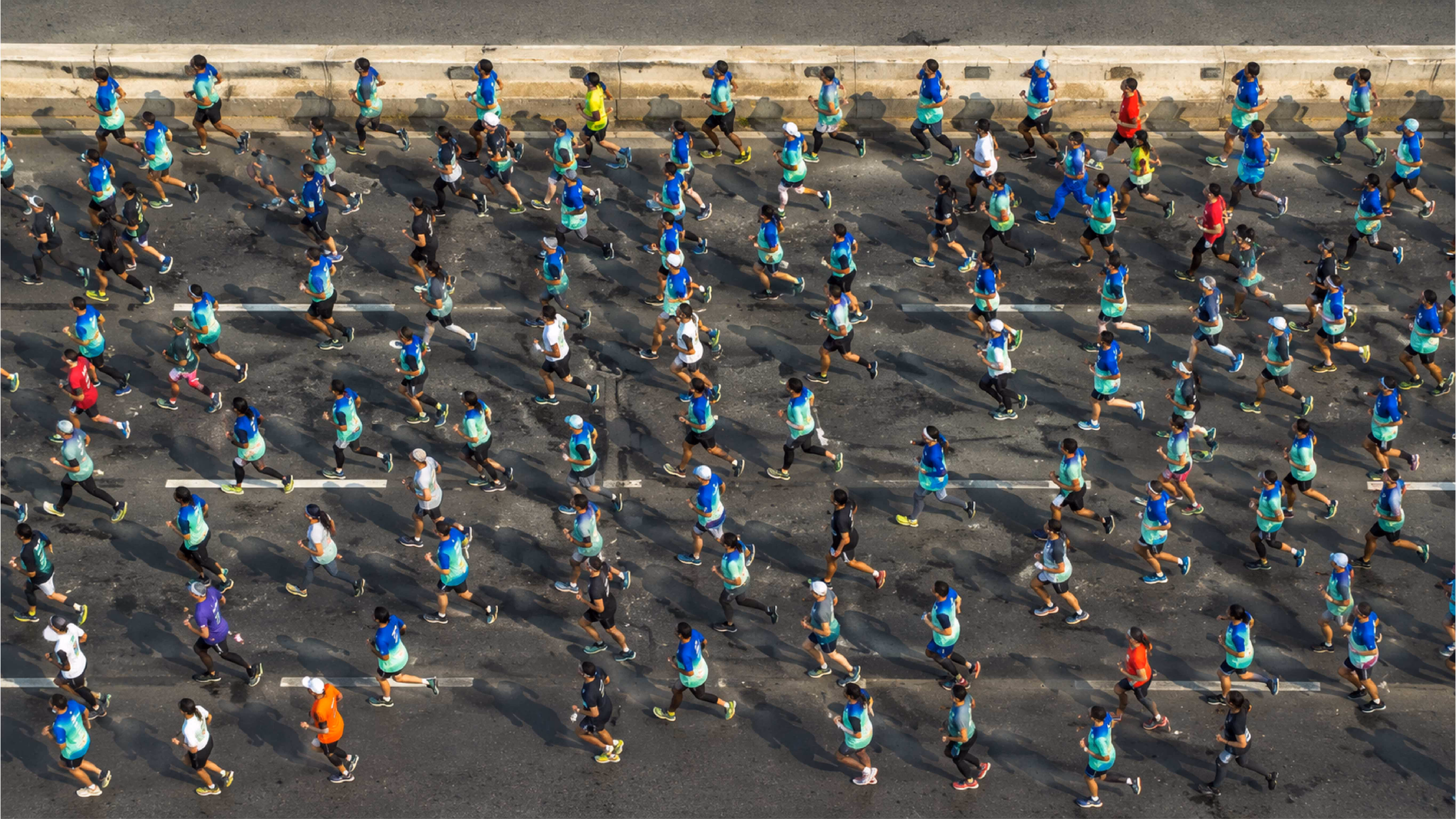 Top view of many runners participating in a marathon on a sunlit city street.