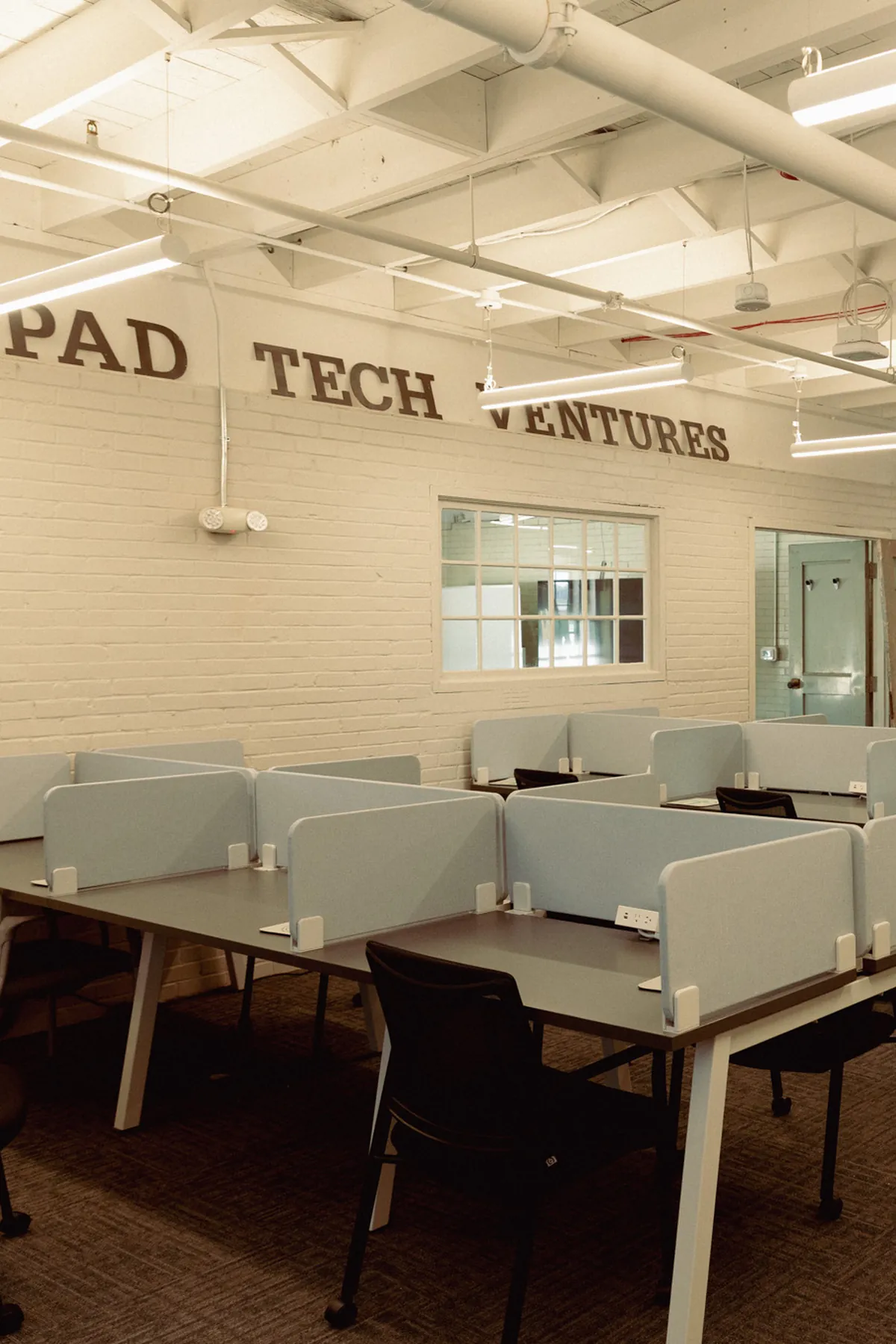 Coworking desks beneath the Launchpad Tech Ventures sign at Tech Village
