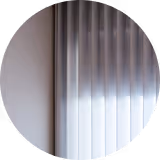 Close-up of light gray and white vertical blinds partially lit by sunlight.