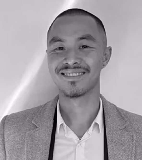 Smiling man with short hair and beard wearing a light blazer and white shirt.