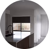 Modern kitchen with dark cabinets, large island, and window showing backyard fence and patio.