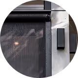 Part of a building exterior with a black window awning and a wall-mounted black rectangular light.