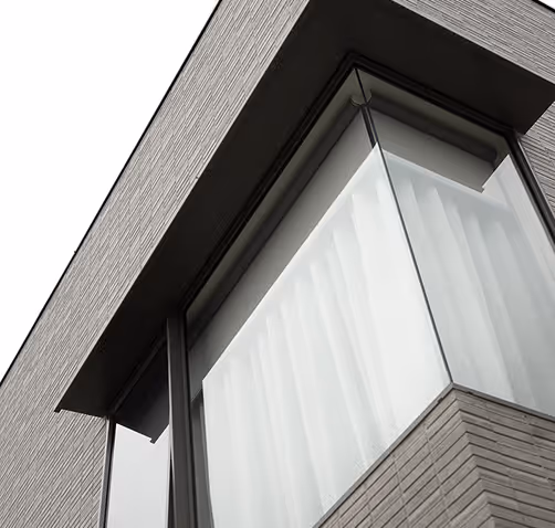 Modern building corner with large glass windows covered by translucent white curtains.