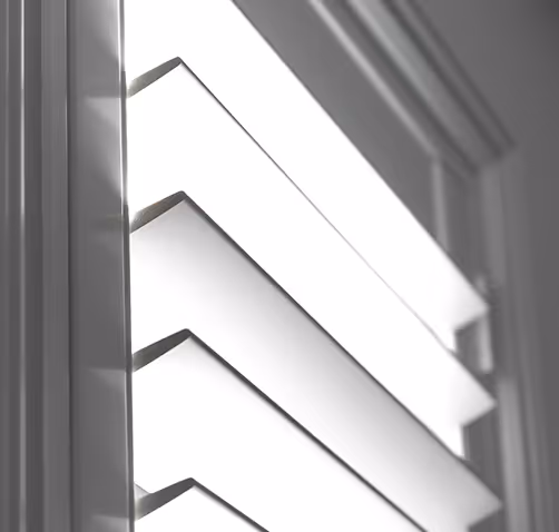 Close-up of white window shutters angled to let light through.