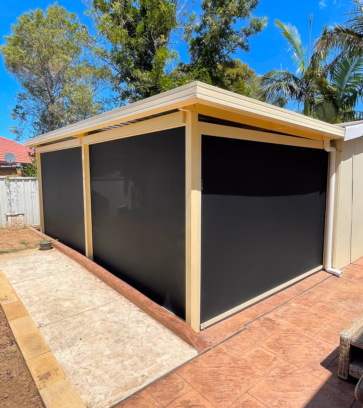 Corner view of a beige-framed outdoor patio enclosure with black sunshade screens.