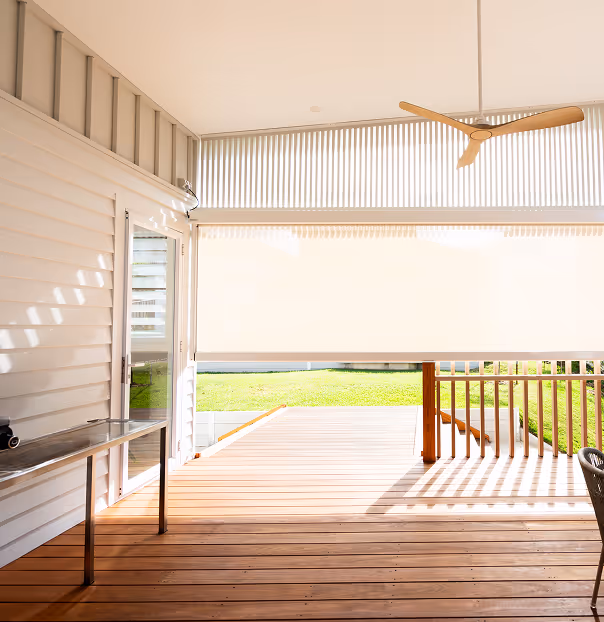 Bright porch with wooden floor, ceiling fan, metal table, and window showing green grass outside.