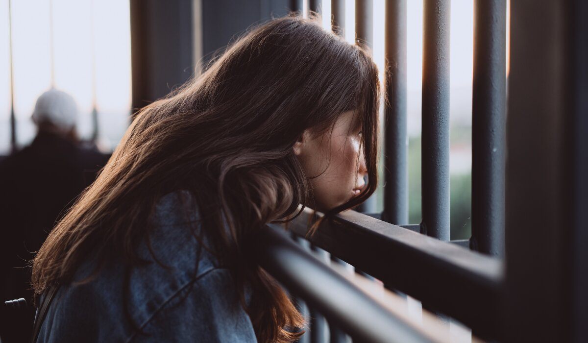 Person sitting alone by a window, looking thoughtful and emotionally overwhelmed before opening up about their feelings.