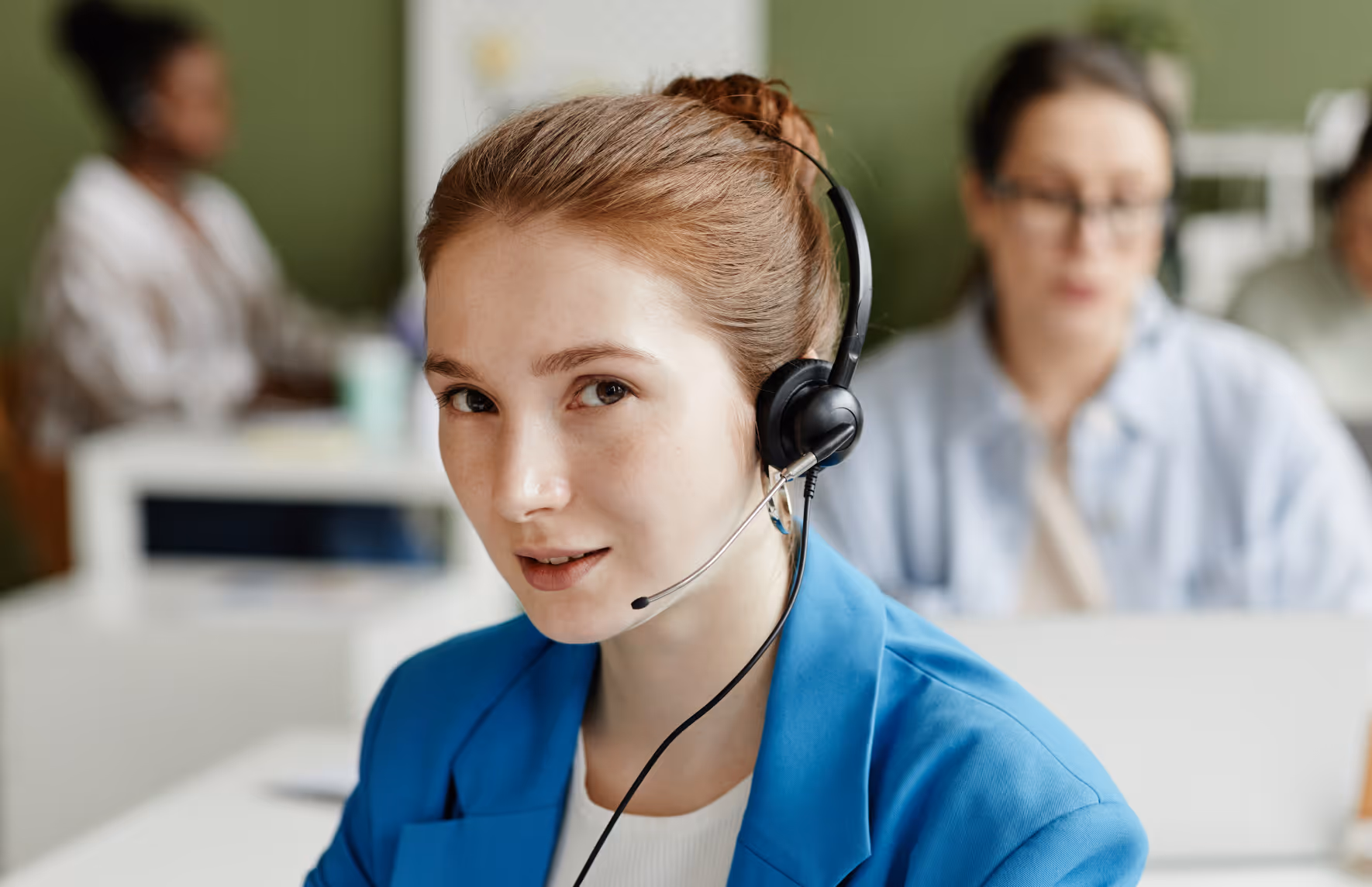 Eine junge Frau hat ein Headset auf und telefoniert in einem vollen Raum.
