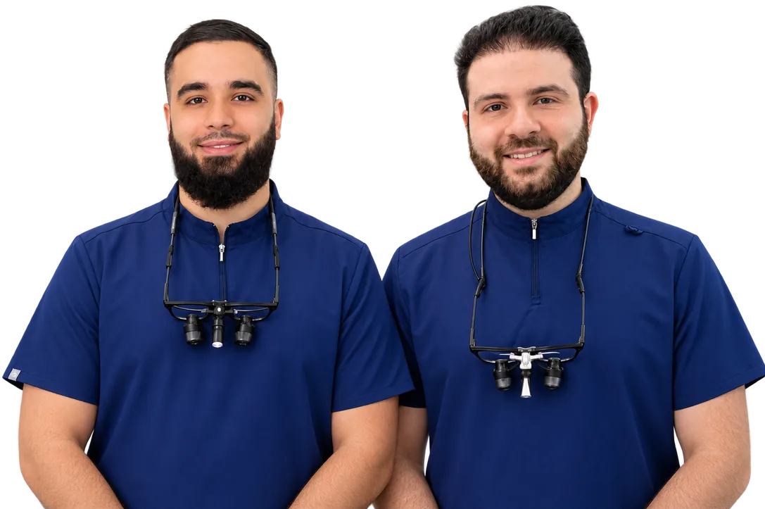 Nadim Elhami and Humzah Aly, oral health therapists at Berala Dental, in navy scrubs wearing dental loupes.