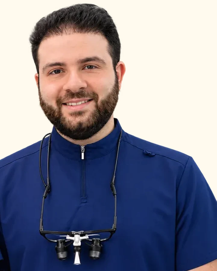 Humzah Aly at Berala Dental, in navy clinical scrubs with dental loupes.