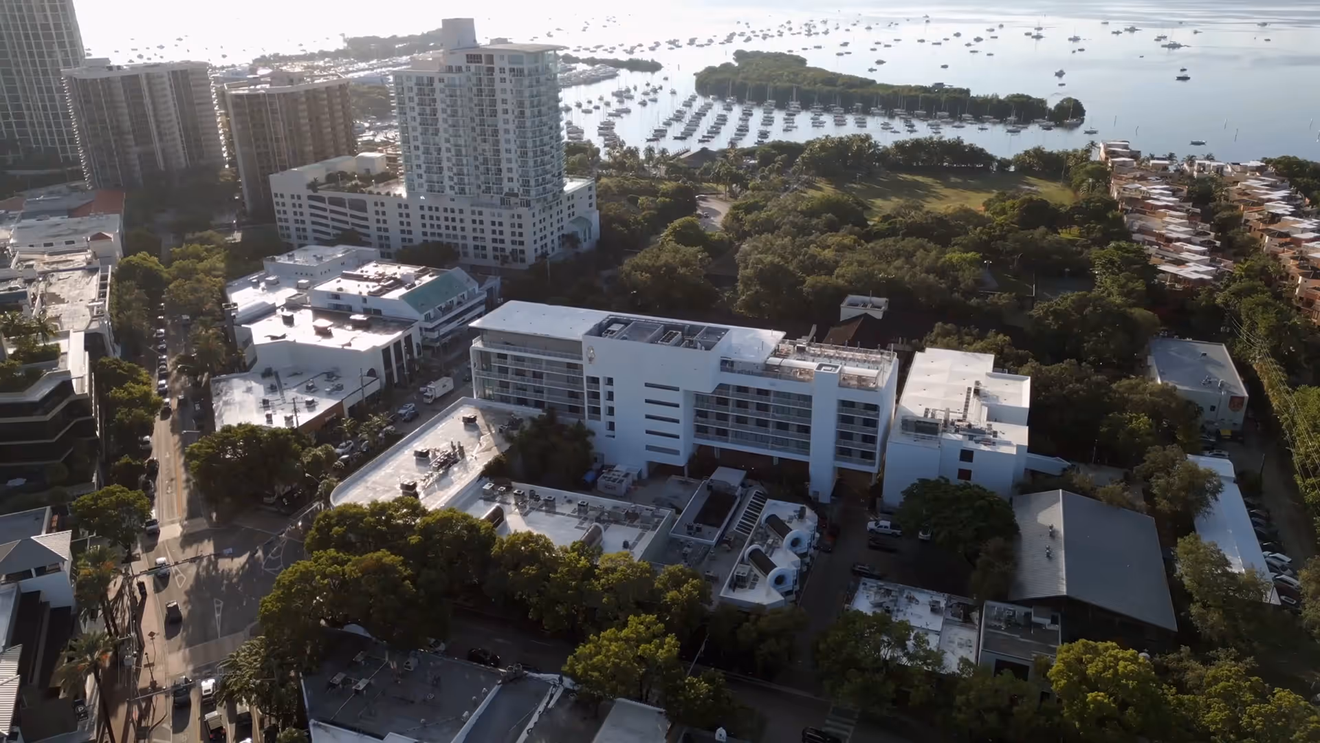 Aerial view of city buildings near a marina filled with boats and surrounded by trees and greenery
, Mr. C Miami – Coconut Grove, luxury hotel.