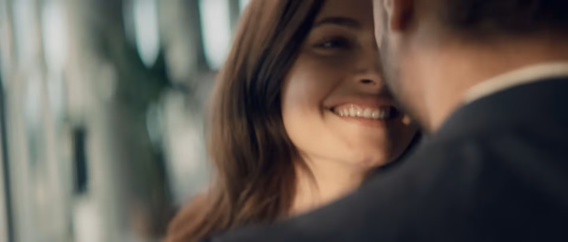 Primo piano di una donna che sorride calorosamente a un uomo in uno sfondo sfocato.