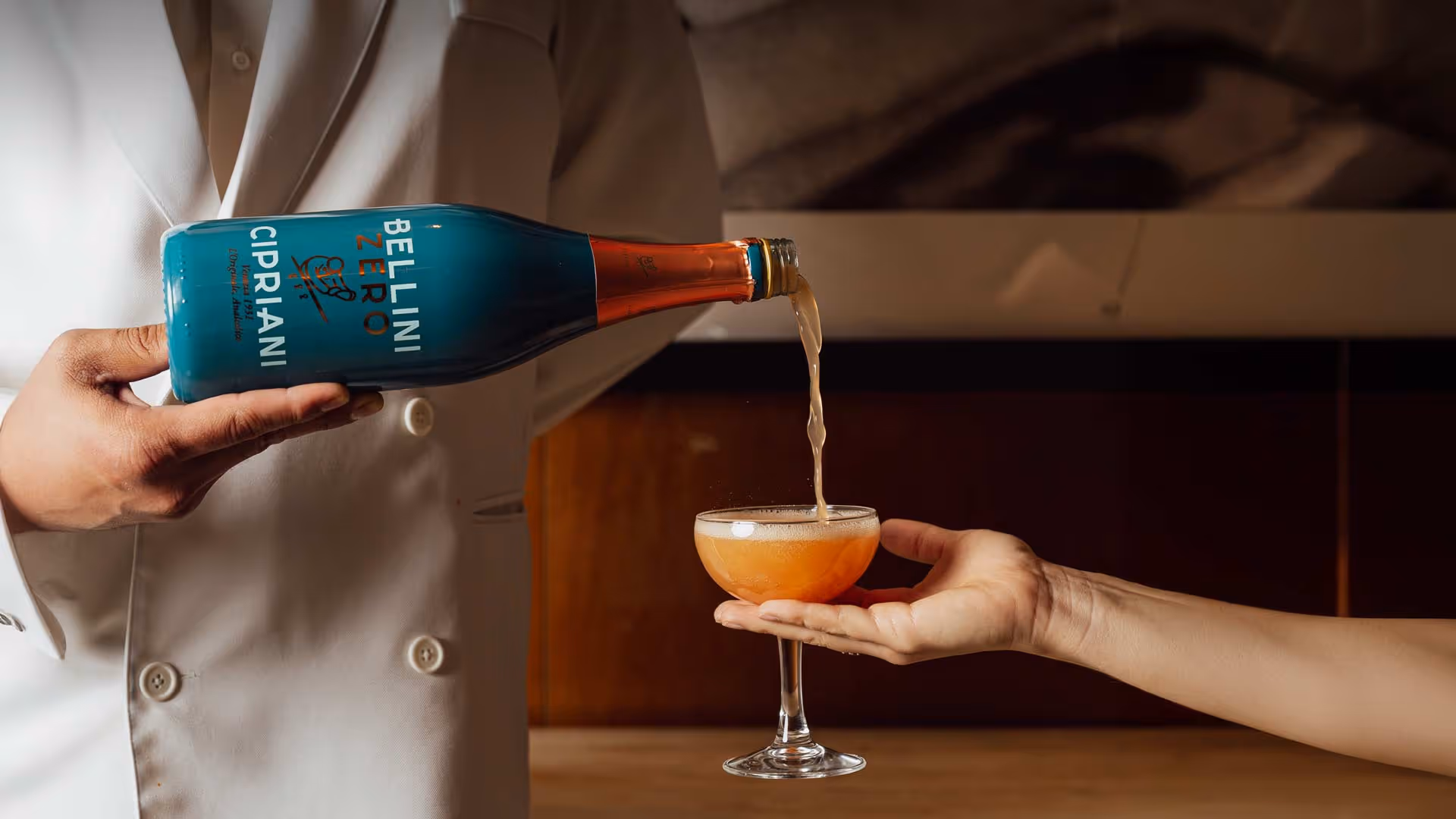 Person in white jacket pouring Cipriani Bellini Zero drink into a cocktail glass held by another hand
, Mr. C Miami – Coconut Grove, luxury hotel.