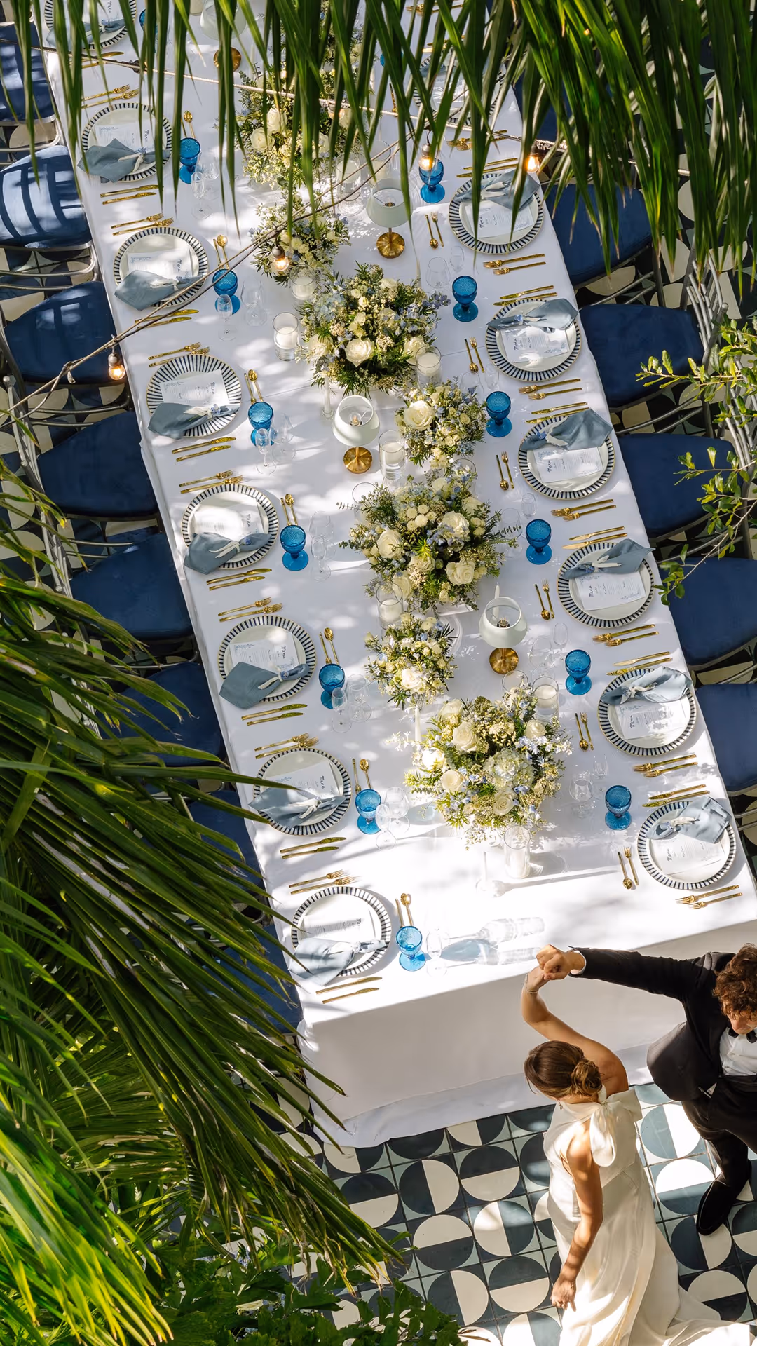 Overhead view of wedding table with blue chairs, flowers, blue glasses, and a dancing couple below, Mr. C Miami – Coconut Grove, luxury hotel.